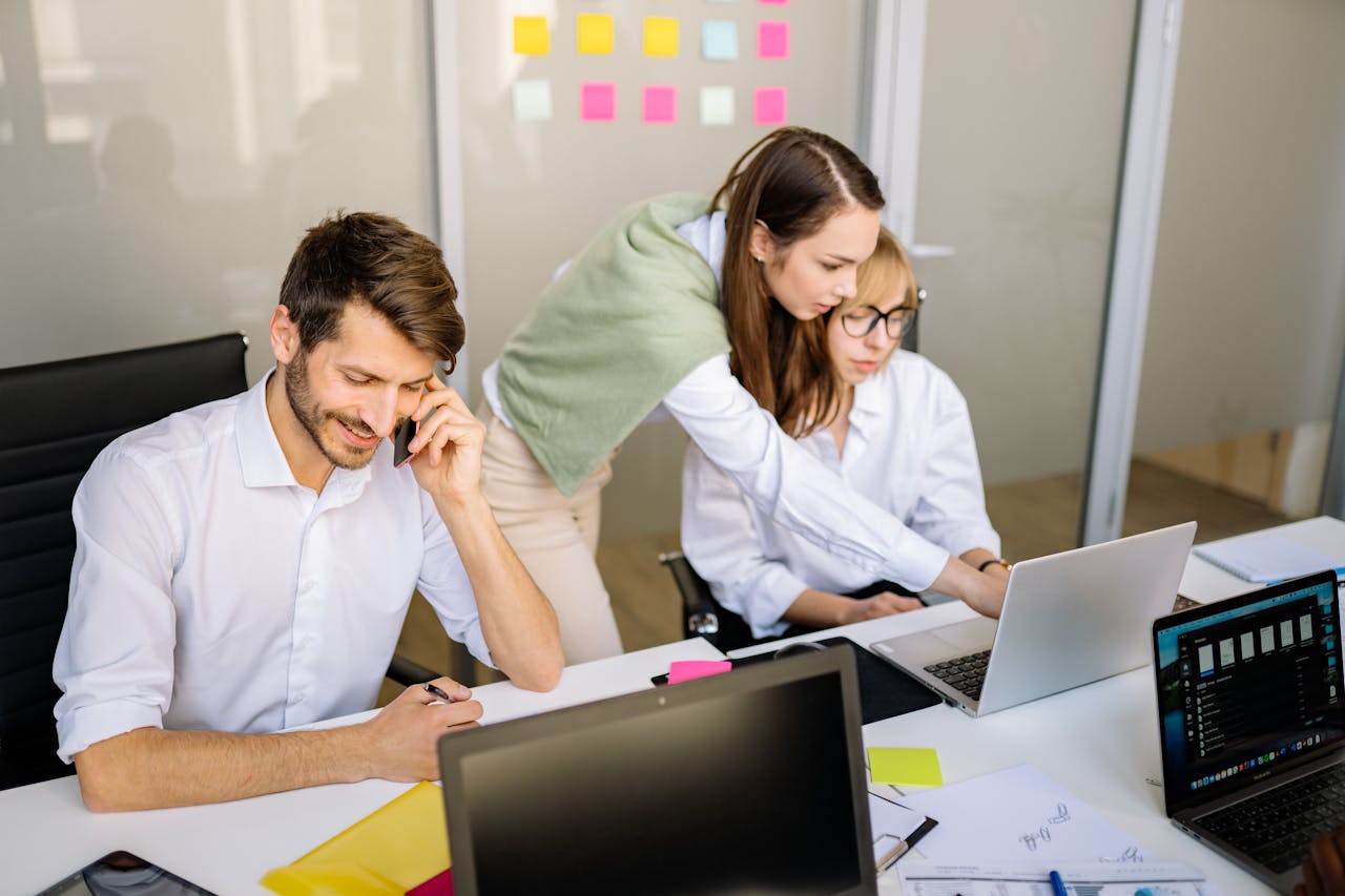 Three professionals engaged in teamwork at a conference table with laptops and notes.
